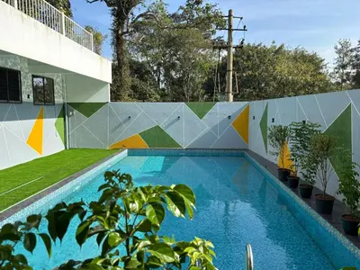 a swimming pool with a mural on a wall at Coorg Le Embera in Virajpet