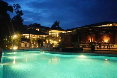 a large swimming pool at night with a building at Inika in Ponnampet