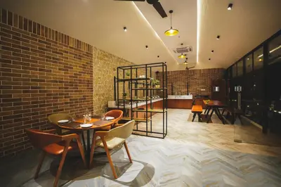 a dining room with a table and chairs and a brick wall at Inika in Ponnampet