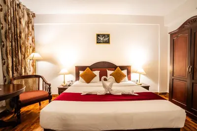 a hotel room with a bed with two swans on it at Hotel C7 Munnar in Munnar