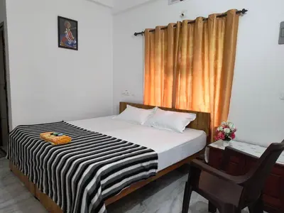 a bedroom with a bed and a chair and a window at GREEN FIELDS Apartments in Mananthavady