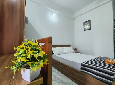 a bedroom with a bed and a vase of yellow flowers at GREEN FIELDS Apartments in Mananthavady
