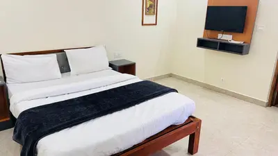a bedroom with a bed with white sheets and a television at Hidden doors in Ooty