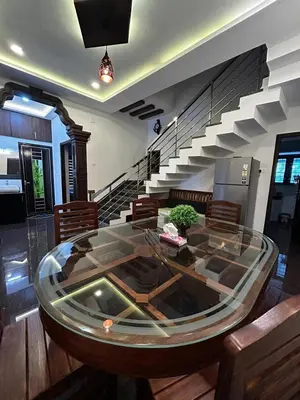 a glass table in a living room with a staircase at Windgram Homestay in Ambalavayal