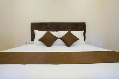 a bed with white sheets and pillows at Grand Plaza Inn in Kottakkal