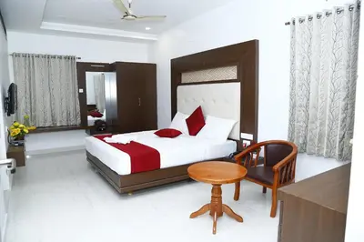 a bedroom with a bed and a table and a chair at Sri Ranga Nivas in Palani