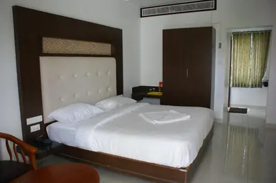a bedroom with a large bed with white sheets at Sri Ranga Nivas in Palani