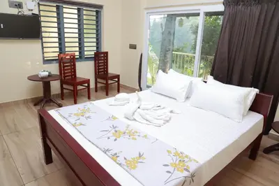 a bedroom with a large bed with chairs and a window at Nisarga Ayurveda in Kizhake Chālakudi