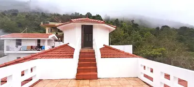 a white building with stairs in front of a mountain at iSTAYS - Kodai Villa in Kodaikānāl