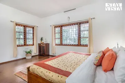 a bedroom with a bed and two windows at StayVista at Wellbeing Villa in Wayanad