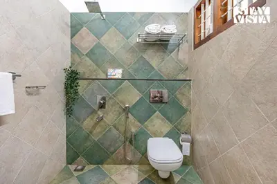 a bathroom with a toilet and a tiled wall at StayVista at Wellbeing Villa in Wayanad