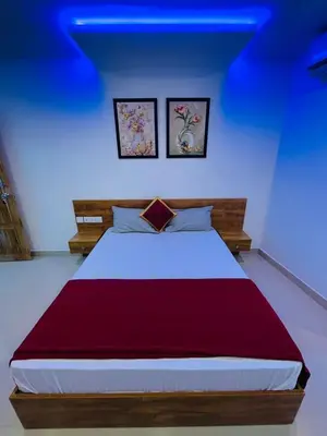 a bedroom with a large bed with two pictures on the wall at Queen C Inn Wayanad in Mānantoddy