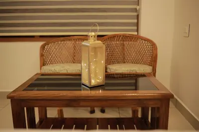 a candle on a table with two wicker chairs at Humblebee Retreat Tattekkad in Kuttampuzha