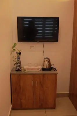 a flat screen tv on a wall above a wooden cabinet at Humblebee Retreat Tattekkad in Kuttampuzha