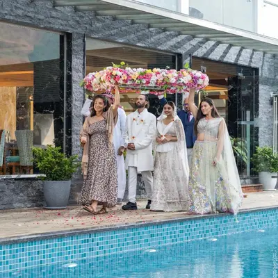 a bride and groom and their wedding party standing under an umbrella at The Grand Cliff Resort Munnar in Viripara