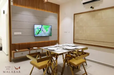 a dining room with a table and a tv on a wall at LUXIE INN MALABAR in Perintalmanna