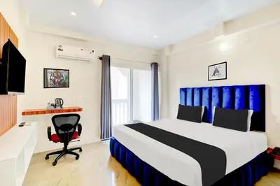 a bedroom with a bed and a desk and a chair at Super Townhouse Mysore Central in Mysore