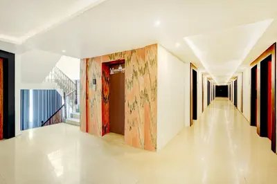 a corridor of a building with white walls and a large painting at Super Townhouse Mysore Central in Mysore