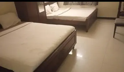 a bedroom with two beds and a chair in it at Renu Residency on the way to Isha yoga centre and near Maruthamalai in Marudhamalai