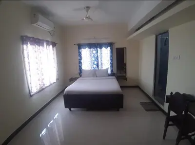 a bedroom with a bed and two windows at Renu Residency on the way to Isha yoga centre and near Maruthamalai in Marudhamalai