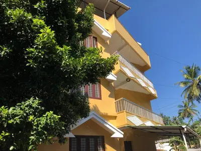 a yellow building with trees in front of it at Angel Valley in Trichūr