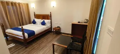 a bedroom with a bed and a table and a chair at COASTAL GRAND RESORT - KOTAGIRI in Kotagiri