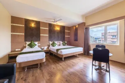 a hotel room with two beds and a window at Treebo ESS Grande in Coimbatore