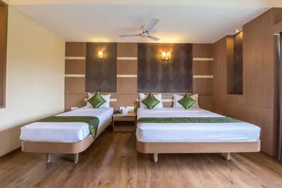 two beds in a room with wooden floors at Treebo ESS Grande in Coimbatore