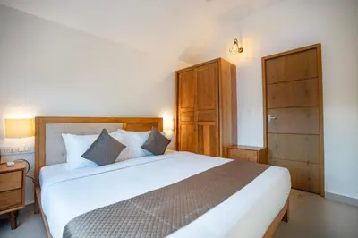 a bedroom with a large white bed and wooden cabinets at Feel Free Retreat in Kalpetta