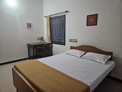 a bedroom with a bed and a desk and a window at SHI's Velliangiri 3BHK Individual villa Near Isha Adiyogi, Coimbatore in Alāndurai