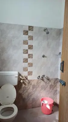 a bathroom with a toilet and a shower with a bucket at SHI's Velliangiri 3BHK Individual villa Near Isha Adiyogi, Coimbatore in Alāndurai