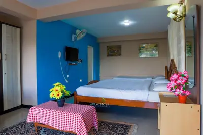 a bedroom with a bed and a table with flowers on it at Vijaya Deepa Guest House by LexStays in Coonoor