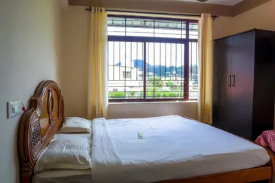 a bed in a room with a large window at Vijaya Deepa Guest House by LexStays in Coonoor