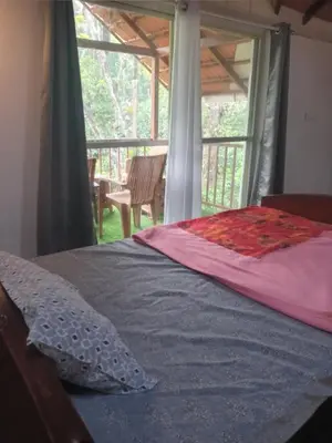 a bed in a bedroom with a view of a porch at Coorg klusters estate stay in Virajpet