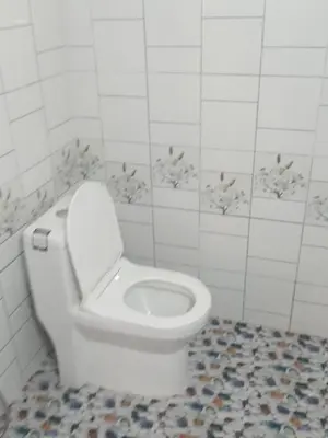 a white toilet in a white tiled bathroom at Coorg klusters estate stay in Virajpet