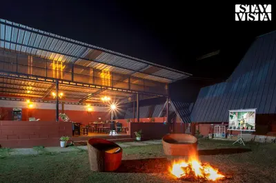 a fire pit in front of a building at night at Golden Triangle by VEO - Part of StayVista in Hampāpura