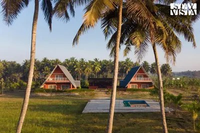 a group of palm trees in front of a house at Golden Triangle by VEO - Part of StayVista in Hampāpura