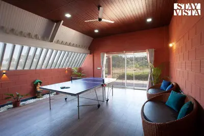a room with a ping pong table and two chairs at Golden Triangle by VEO - Part of StayVista in Hampāpura