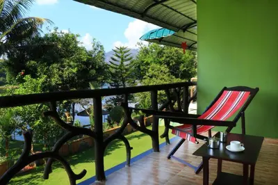 a balcony with a red chair and a table with a view at Elephant Pass Ayurveda & Yoga Retreat in Malayāttūr