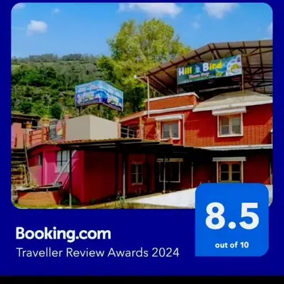 a sign that says travel review awards with a red building at HILL BIRD HOME STAY Ooty in Ooty