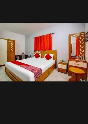 a bedroom with a large bed with red curtains at HILL BIRD HOME STAY Ooty in Ooty