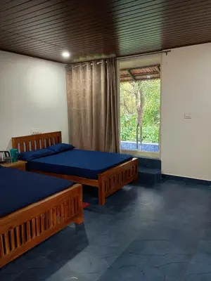 two beds in a room with a window at Nature Spot Cottages Coorg in Kurchi