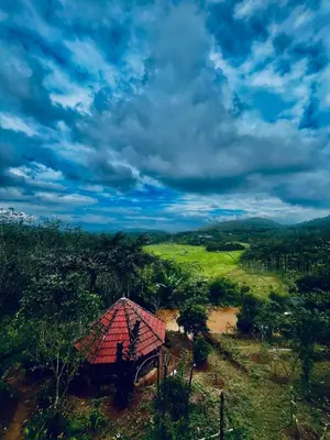 a small house with a red roof in a field at Angels Nest Home stay 2 Acra private plantation Mountain area balconey SunRice view Nearby Ngarhole wild life , Tholpetty wild life , Pakshipathalam Bird santuary , Kuruva island # Thirunelly & Thrissilery Temple Near by Secure Stay Wayanad Kerala in Chekadi