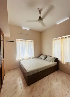 a bedroom with a large bed with two windows at Homestay Guruvayur, 2 AC Bedrooms, Hall, Veranda, Kitchen in Guruvāyūr