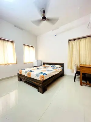 a bedroom with a bed in the middle of a room at Guruvayur Homestay - 2 AC Bedrooms, Hall & Veranda in Guruvāyūr