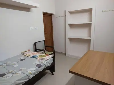 a room with a bed and a chair and shelves at Guruvayur Homestay - 2 AC Bedrooms, Hall & Veranda in Guruvāyūr