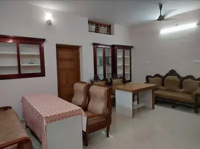 a living room with a table and some chairs and a table and a tablektop at Guruvayur Homestay - 2 AC Bedrooms, Hall & Veranda in Guruvāyūr