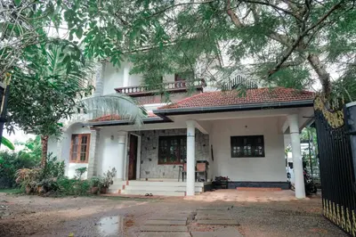 a white house with a balcony on top of it at Sankalpa Homestay in North Paravur