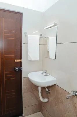 a bathroom with a sink and a mirror and towels at Sankalpa Homestay in North Paravur