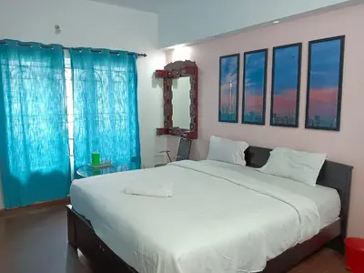 a bedroom with a large white bed with blue curtains at Savi's home stay in Ooty